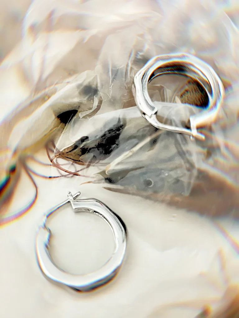 Wave design silver polygon bubble earrings, reflective polished finish, medium small hoop size reference on hand.