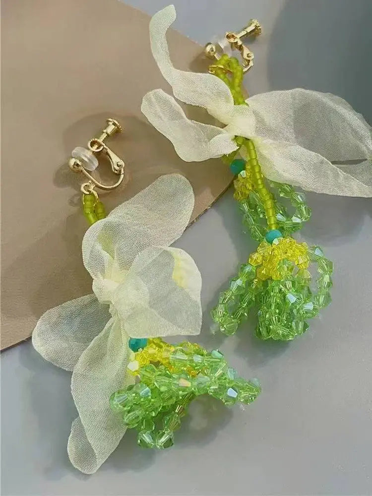 La fée verte tisse des boucles d'oreilles