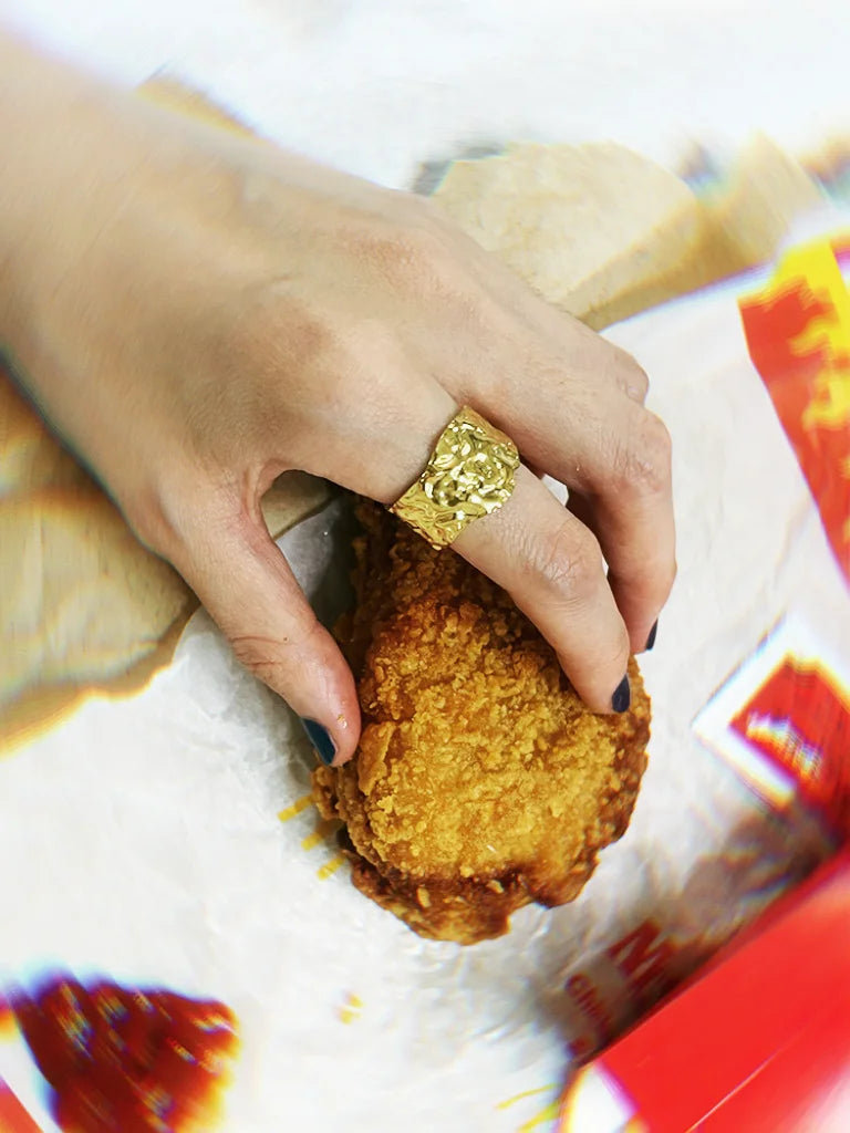 Fairies Whisper Venus de Milo Ring worn on hand touching fried chicken, imperfect textured gold jewelry with dramatic contrast