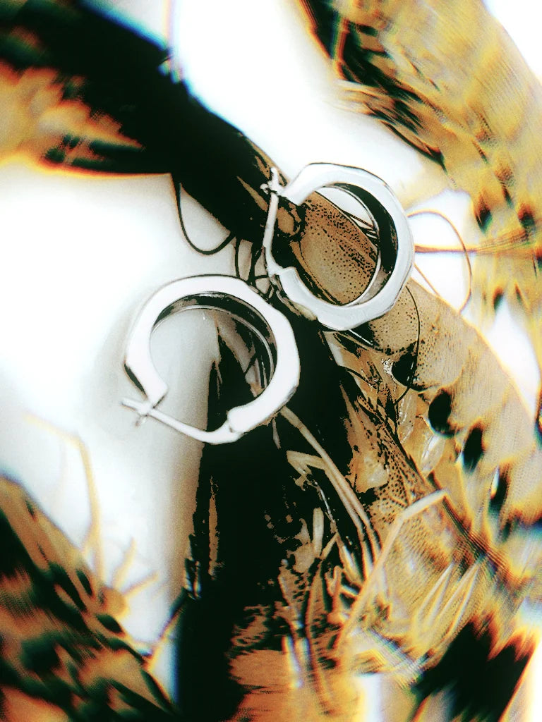 Silver polygon wave hoop earrings with bubble texture, compact medium small size, hand comparison for proportion.