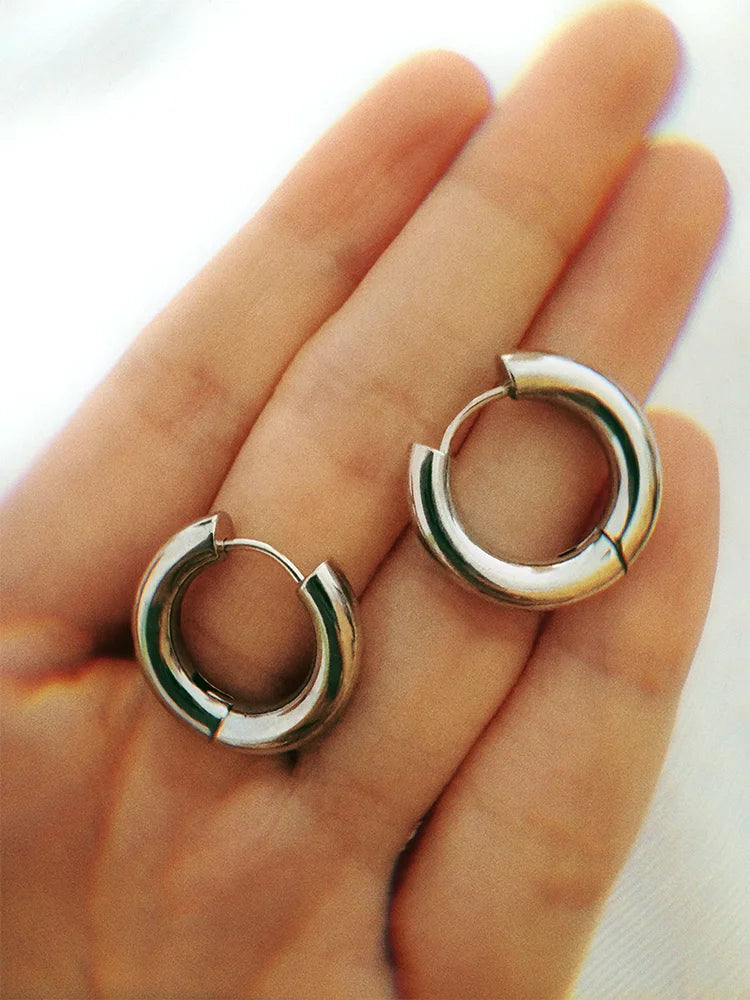 Fairies Whisper Fish Market Silver Silver polished Fish Eye earrings from FW Cold Appetite series, shown on hand for scale, width similar to a finger.